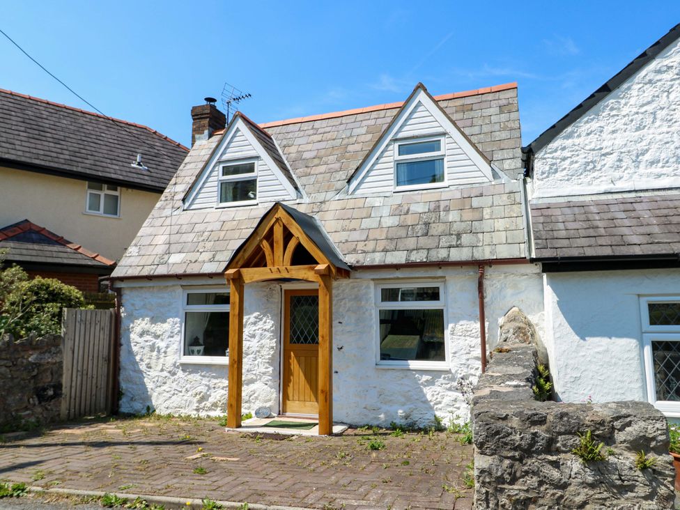 A cottage with a wooden door and windows at Bryn Pydew in Llandudno Junction