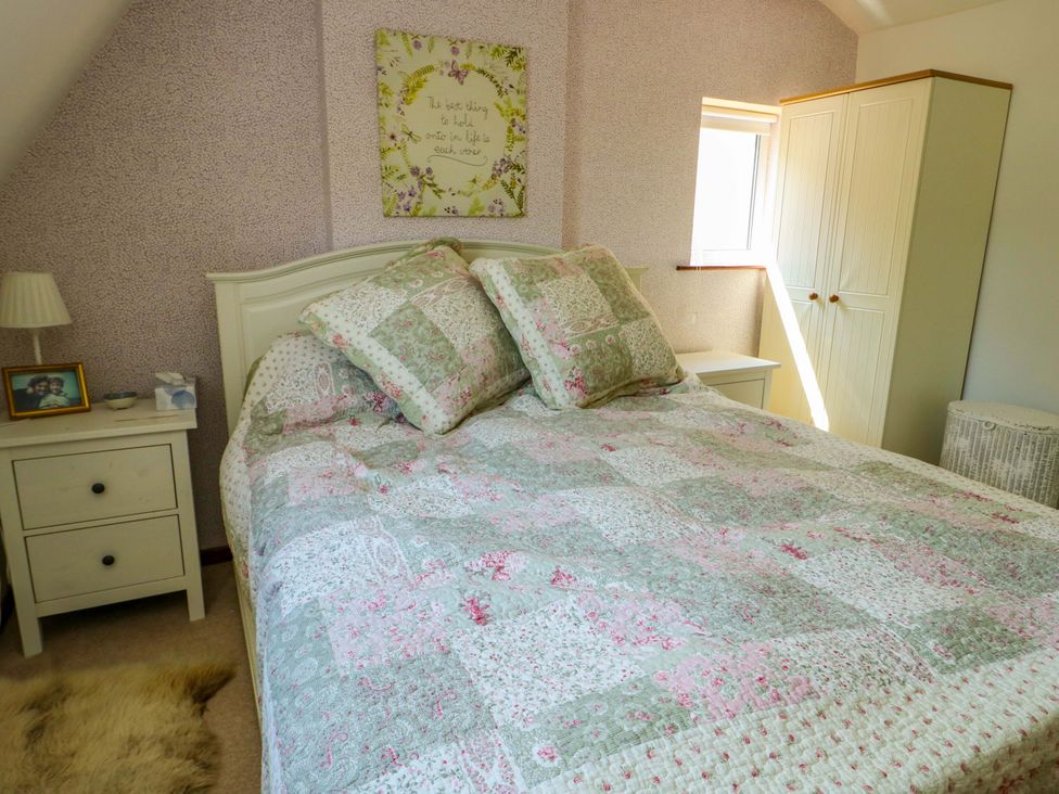 A bedroom with a bed, nightstand, and wardrobe at Bryn Pydew in Llandudno Junction