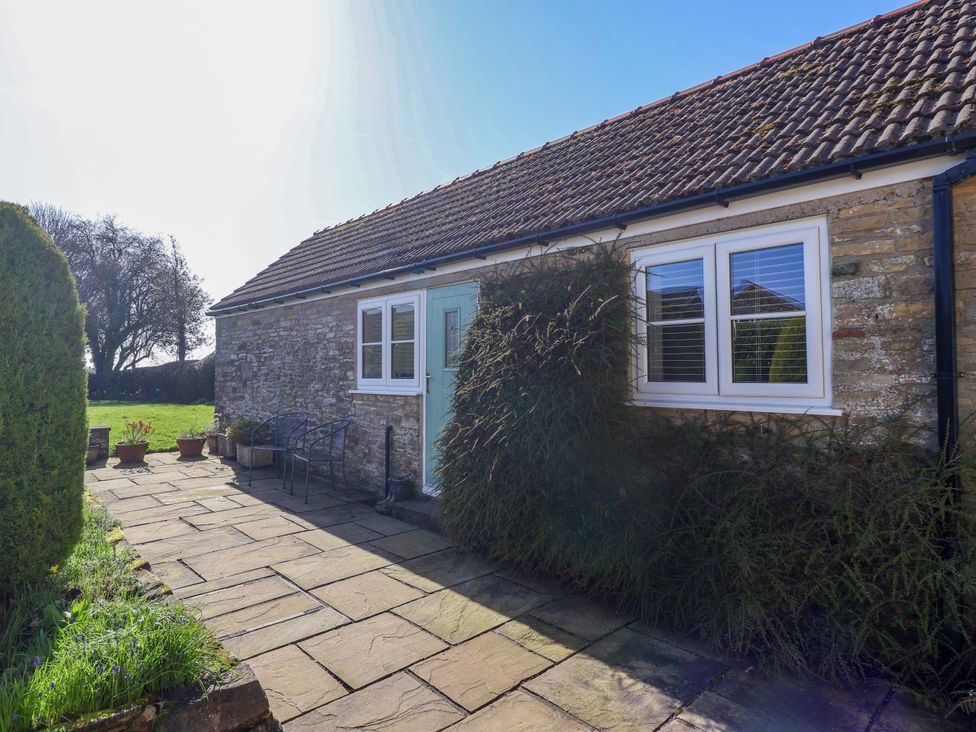 A house entrance with stone path and plants at Cartwheel Cottage in Yearsley