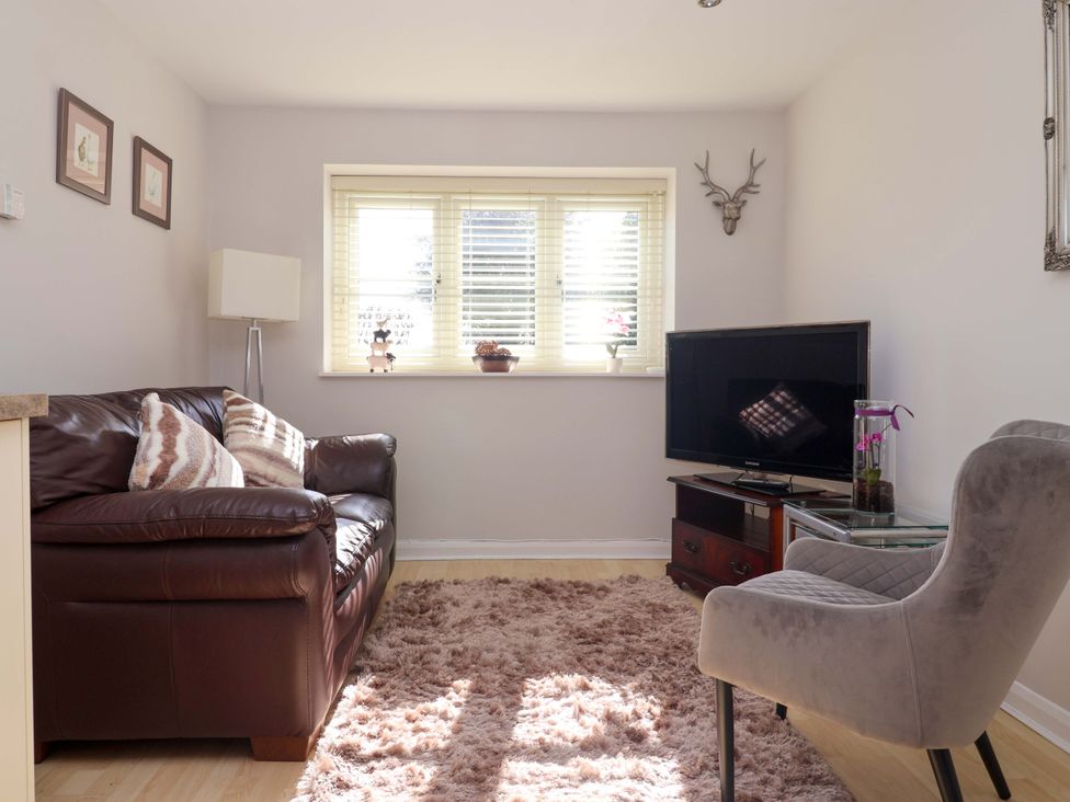 A living room with a sofa and television at Cartwheel Cottage in Yearsley