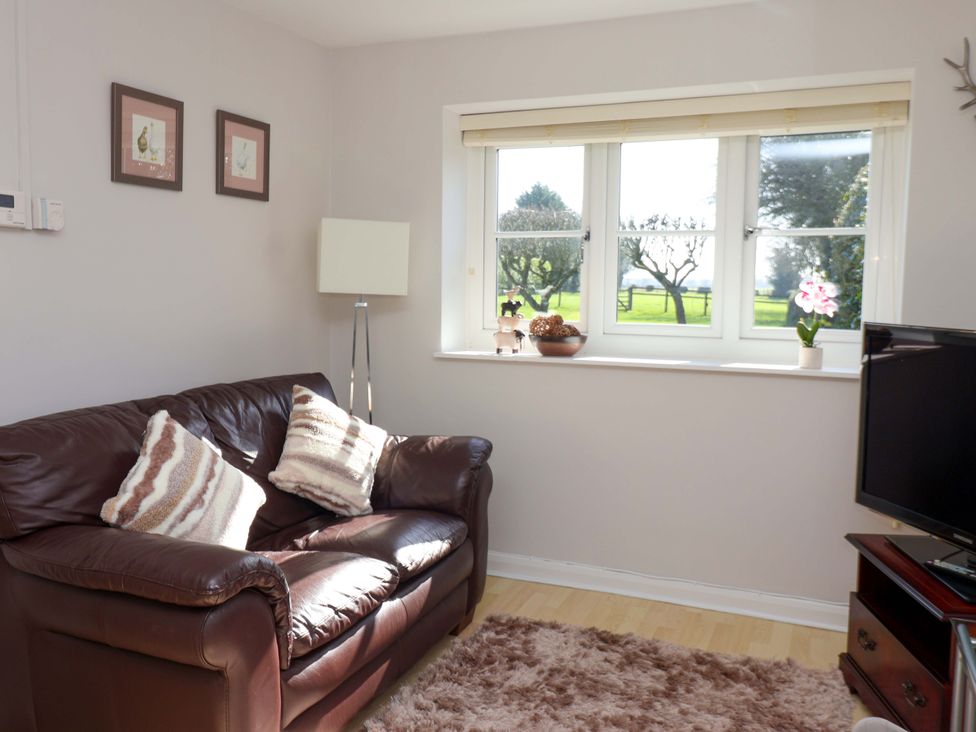 A living room with a sofa and window at Cartwheel Cottage in Yearsley
