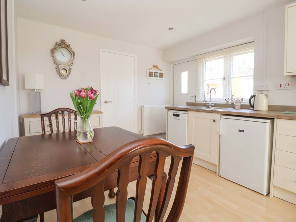 A kitchen with table and flowers at Cartwheel Cottage in Yearsley