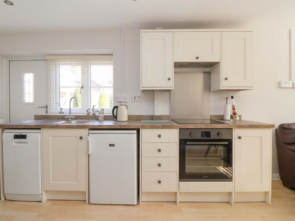A kitchen with a sink, fridge, oven and dishwasher at Cartwheel Cottage in Yearsley