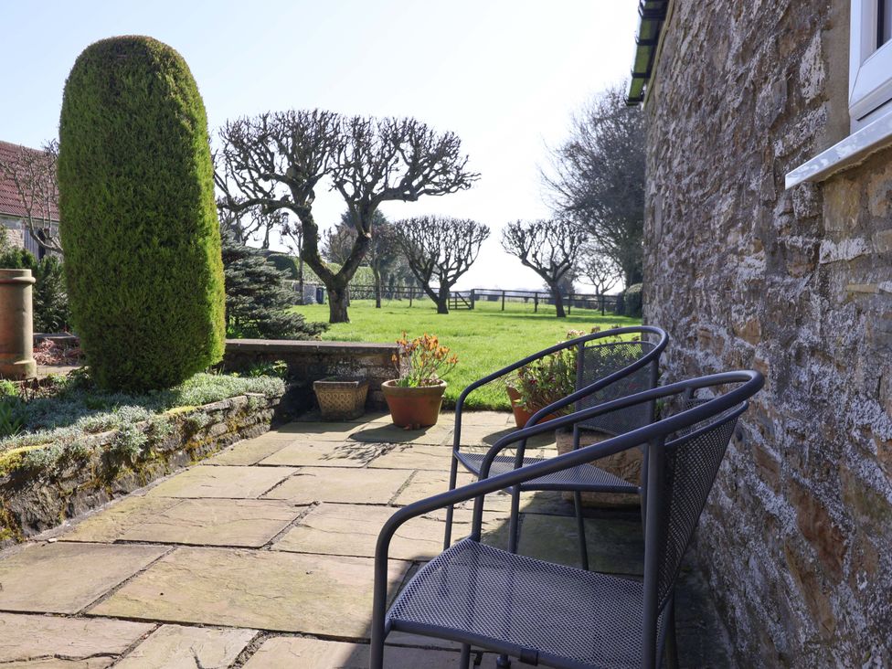 A garden with chairs and plants at Cartwheel Cottage in Yearsley