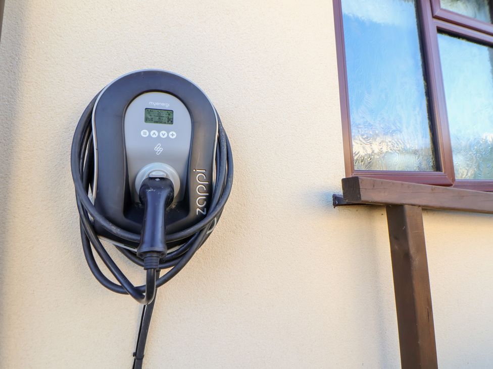 An electric vehicle charger mounted on a wall at Arosfa in Axton near Trelawynd