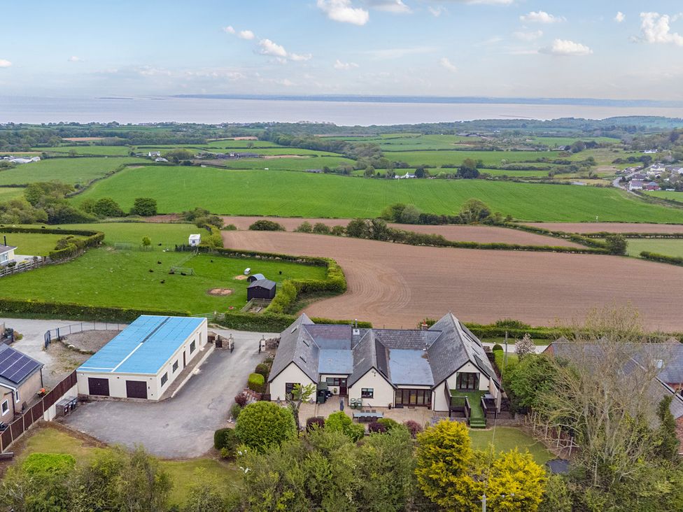 An aerial view of a house and barn with fields near Arosfa Axton near Trelawynd