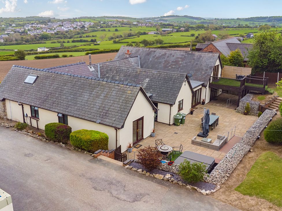 An outdoor view of a house with a garden and patio at Arosfa Axton near Trelawynd