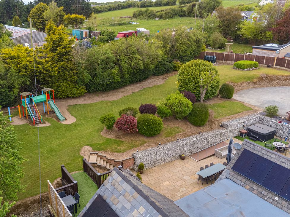 A garden with a playground and seating area at Arosfa in Axton near Trelawynd