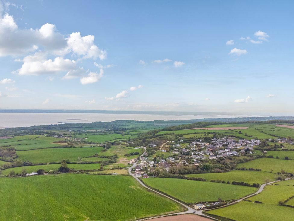 An aerial view of fields and houses near the water at Arosfa in Axton near Trelawynd