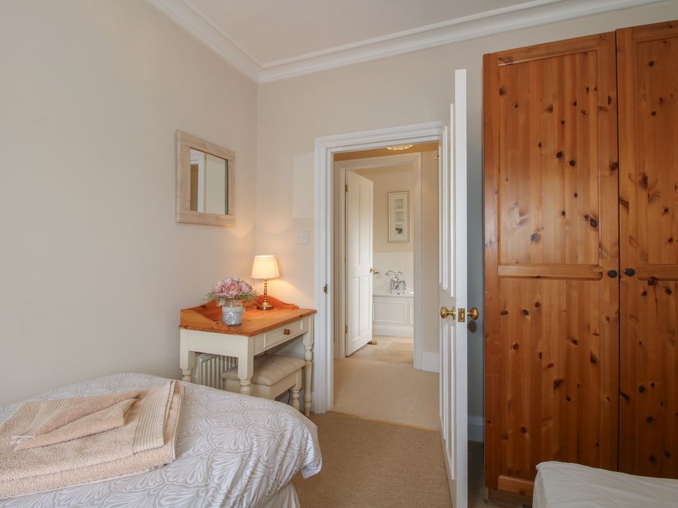 A bedroom with a bed, wardrobe, and a table at The Old Nursery in Bourton near Much Wenlock
