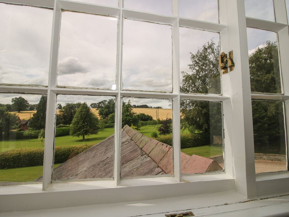 A view from a window showing a landscape with trees and a field at The Old Nursery Bourton near Much Wenlock