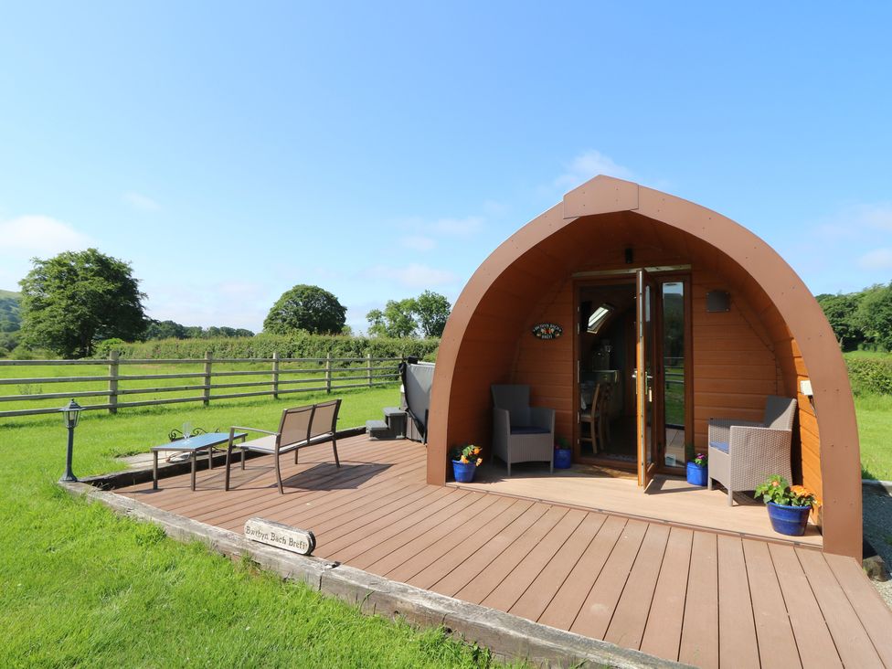 A cabin with a deck and chairs at Bwthyn Bach Brefi