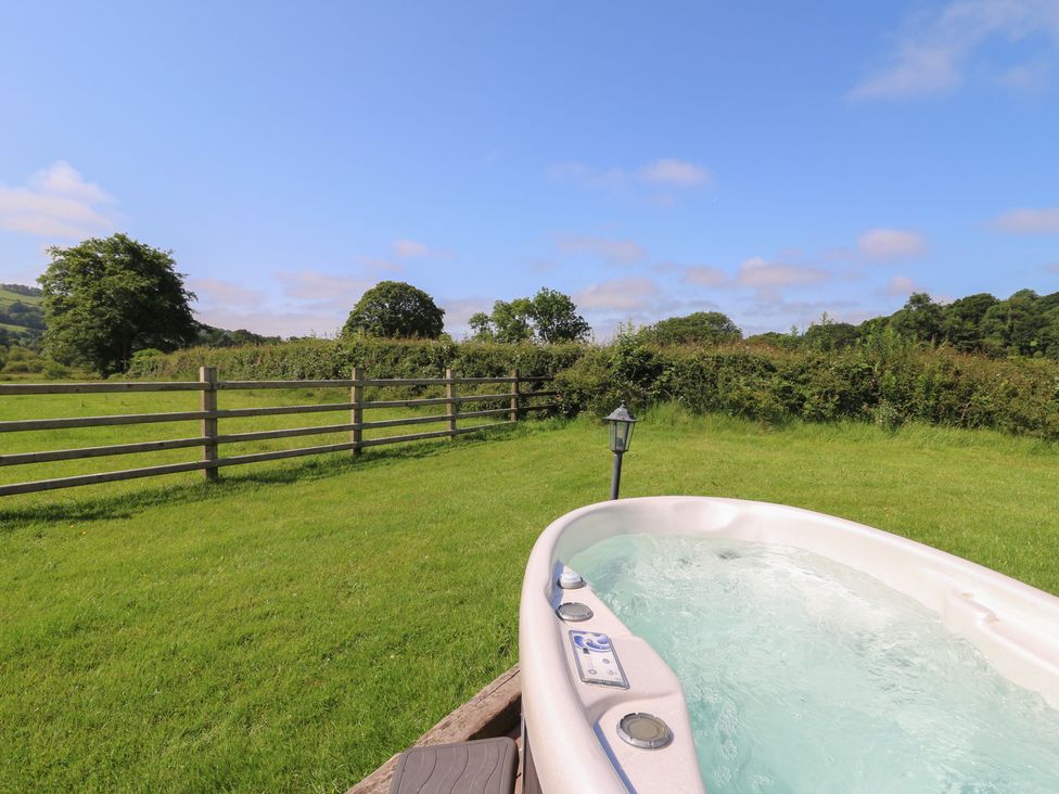 A hot tub in a grassy area surrounded by a fence at Bwthyn Bach Brefi