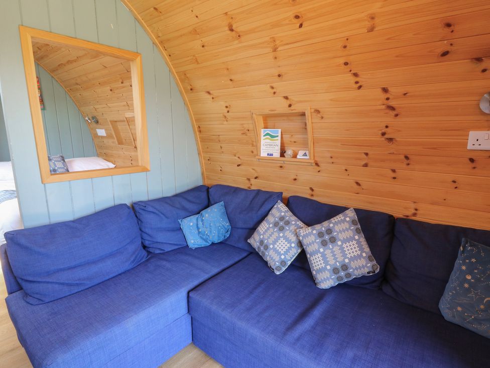 A snug area with a blue sofa and cushions at Bwthyn Bach Brefi