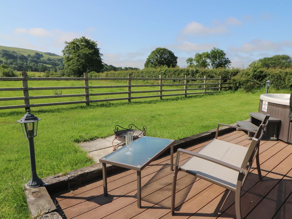 An outdoor area with a table and chairs beside a hot tub at Bwthyn Bach Brefi