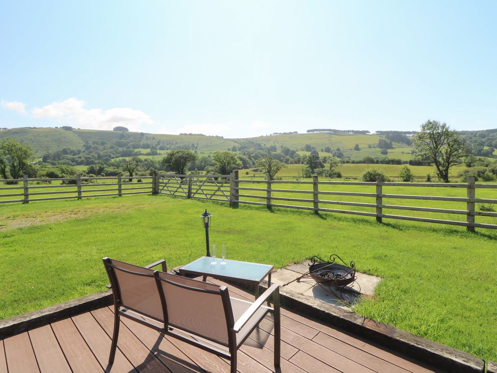 A patio with a chair and table overlooking a grassy field at Bwthyn Bach Brefi