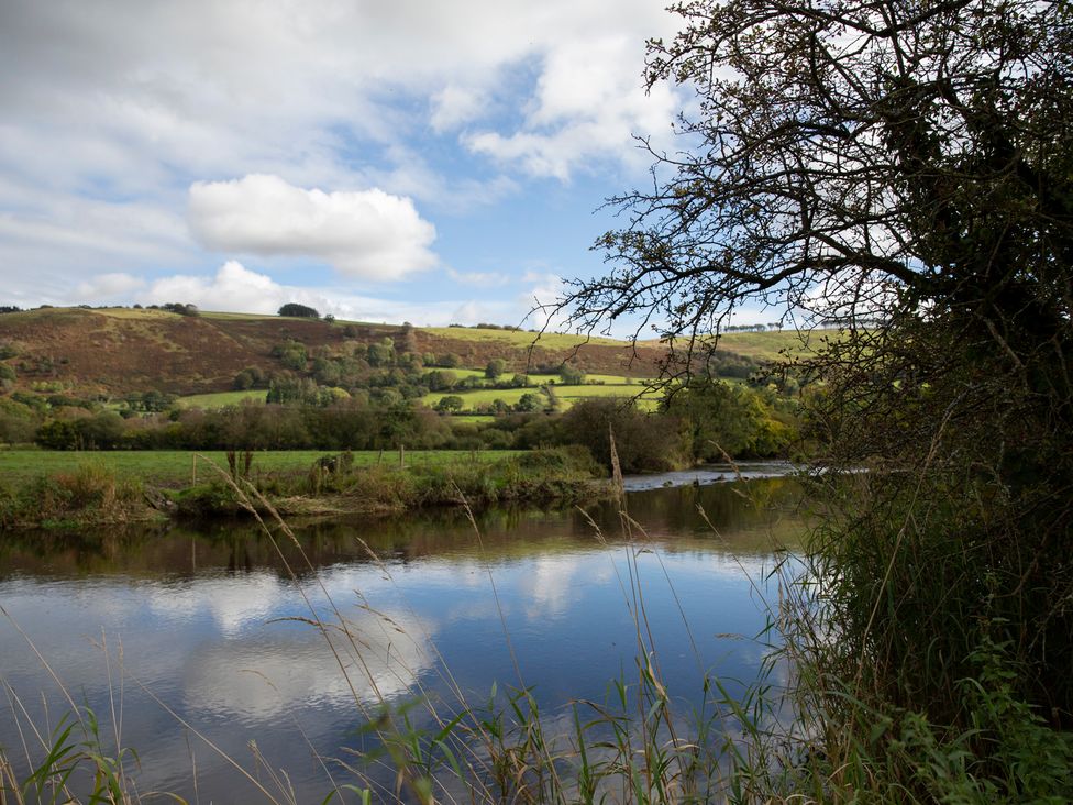 A river surrounded by trees and hills at Bwthyn Bach Brefi
