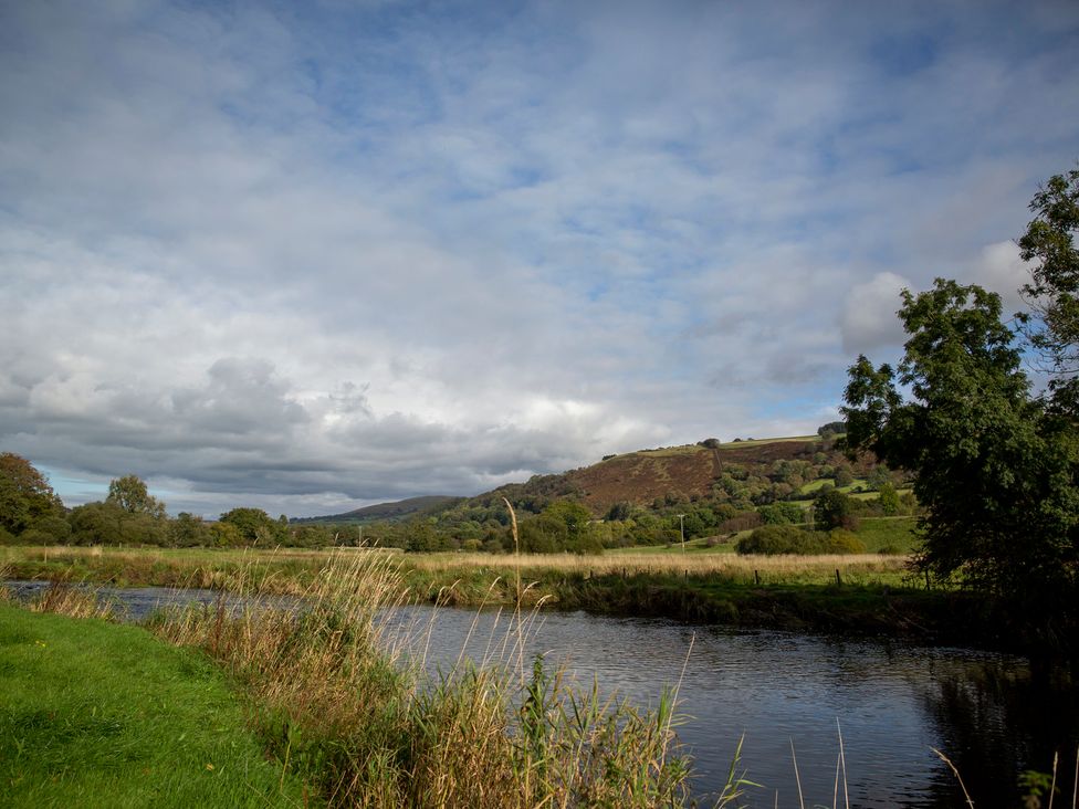A river with trees and hills under a cloudy sky at Bwthyn Bach Brefi
