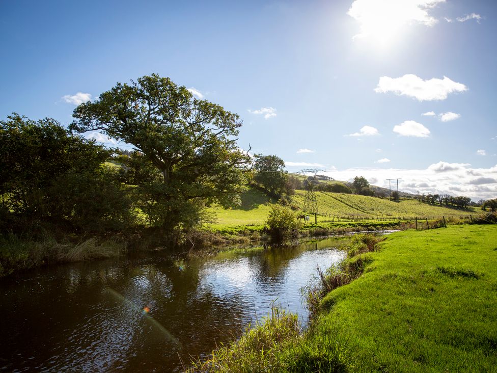 A river with trees and power lines in a rural area at Bwthyn Bach Brefi