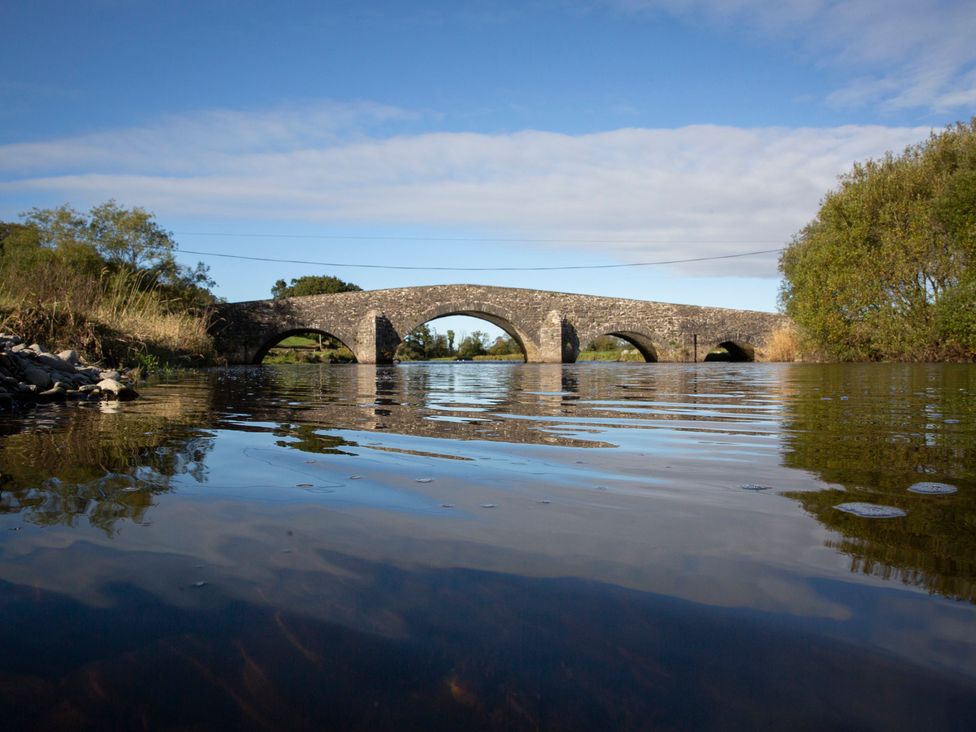 A bridge over a river with trees and a clear sky at Bwthyn Bach Brefi