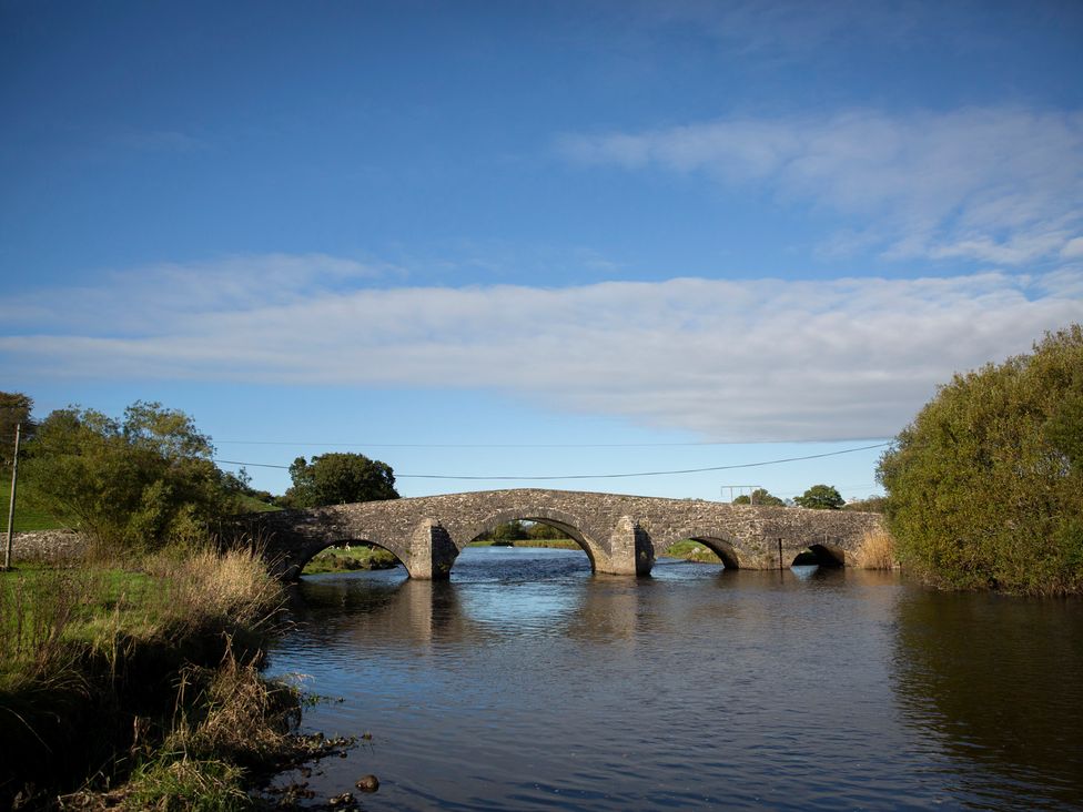 A bridge over a river with trees and grass at Bwthyn Bach Brefi