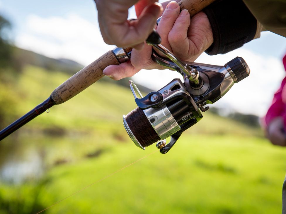 A close-up of a fishing rod and reel with fishing line outdoors at Bwthyn Bach Brefi