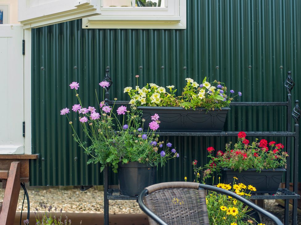 A garden with flower pots on a black metal stand at Onnen Oakford near Aberaeron