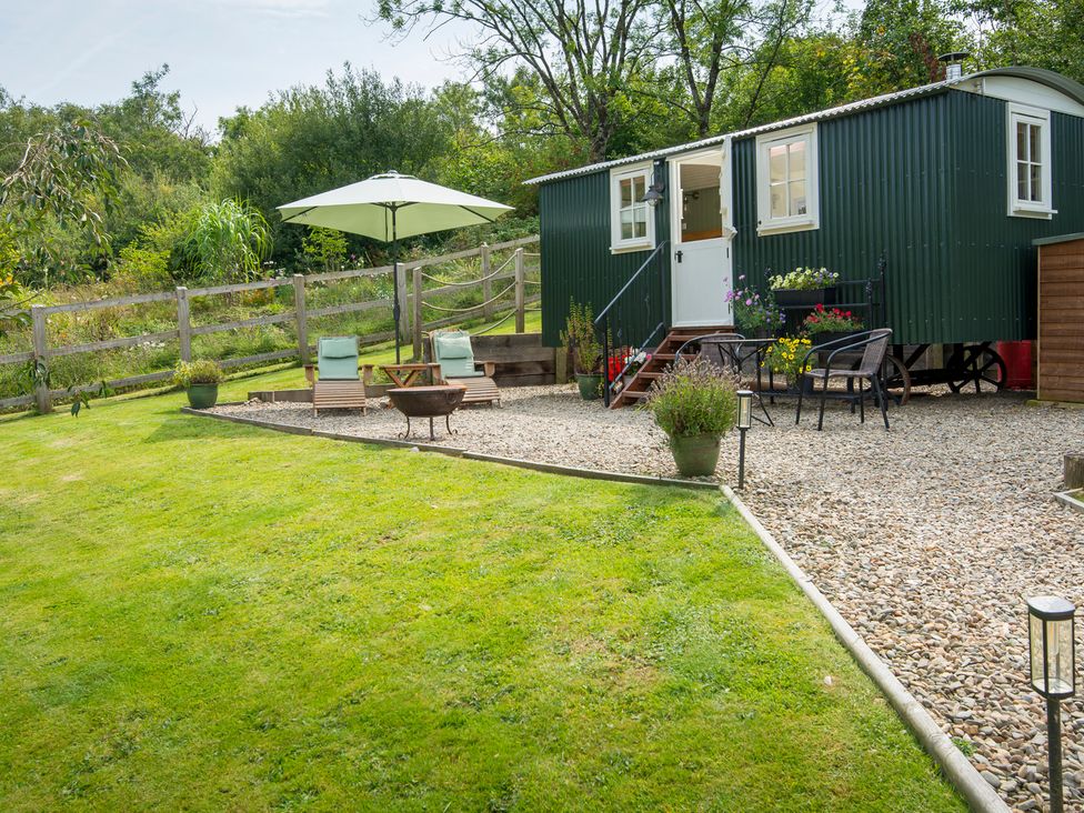 An outdoor area with a green shed and seating at Onnen Oakford near Aberaeron