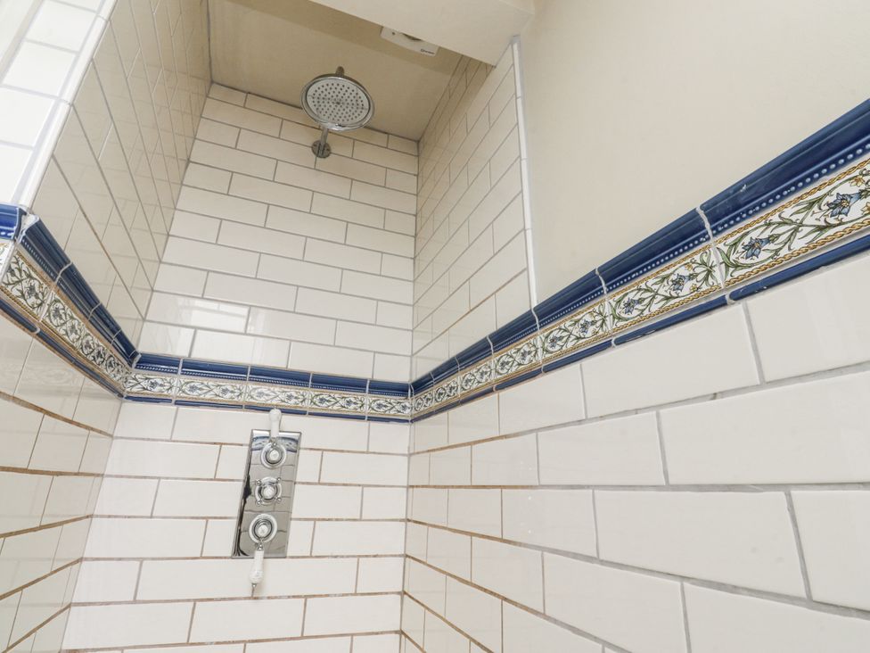 A shower with tiles and a showerhead at Bridgend Cottage Eastby near Embsay