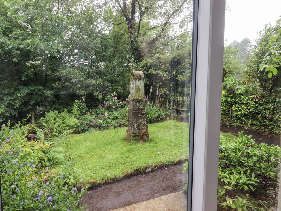 A garden with a stone pillar and flowers at Bridgend Cottage Eastby near Embsay