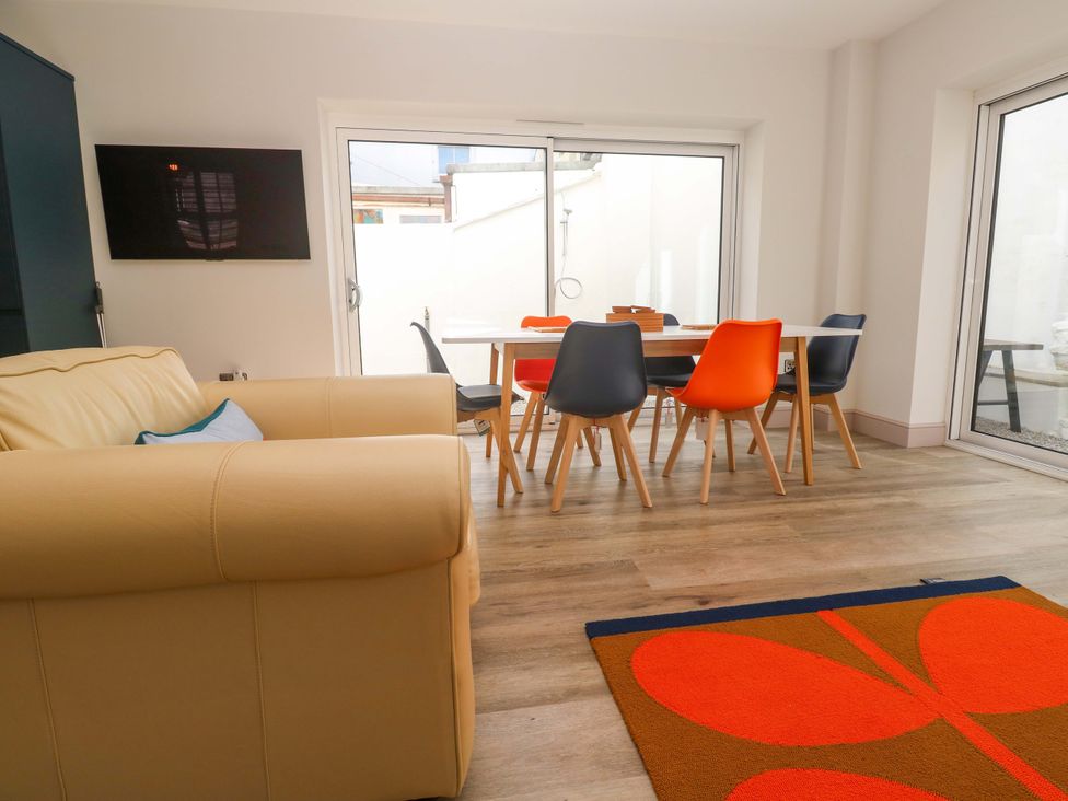 A living room with a sofa and dining area at 21 Alverton Street in Penzance