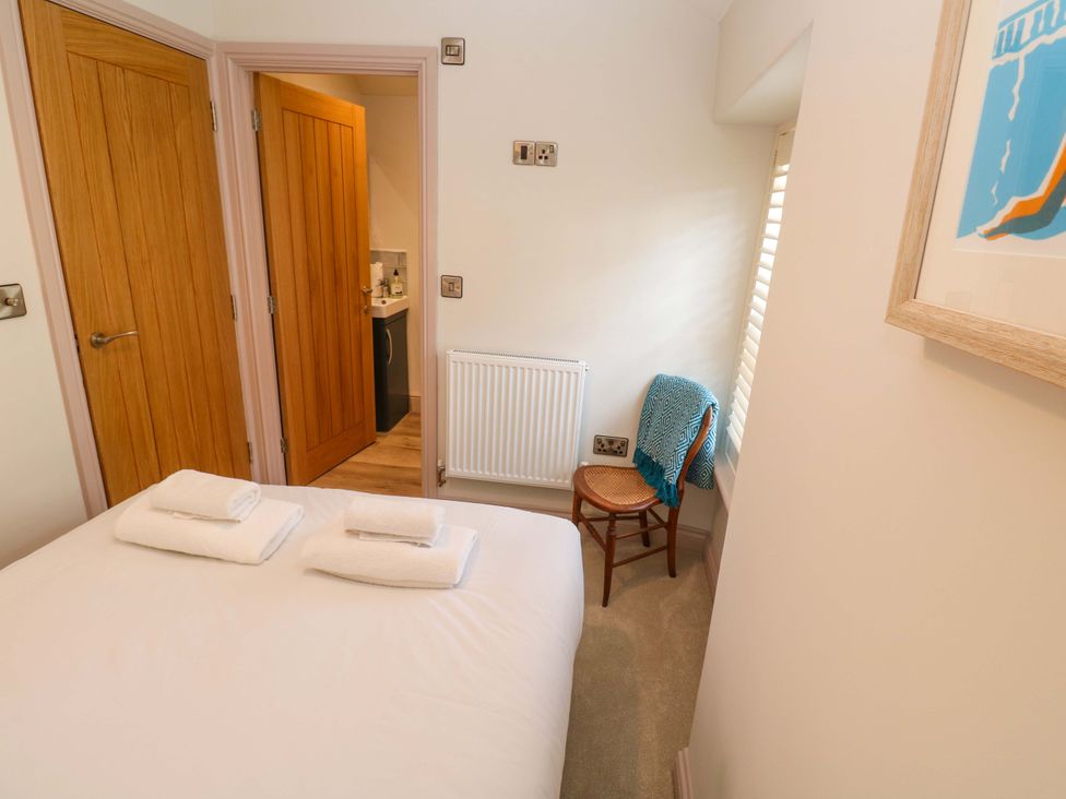 A bedroom with a bed, towels, and a chair at 21 Alverton Street in Penzance