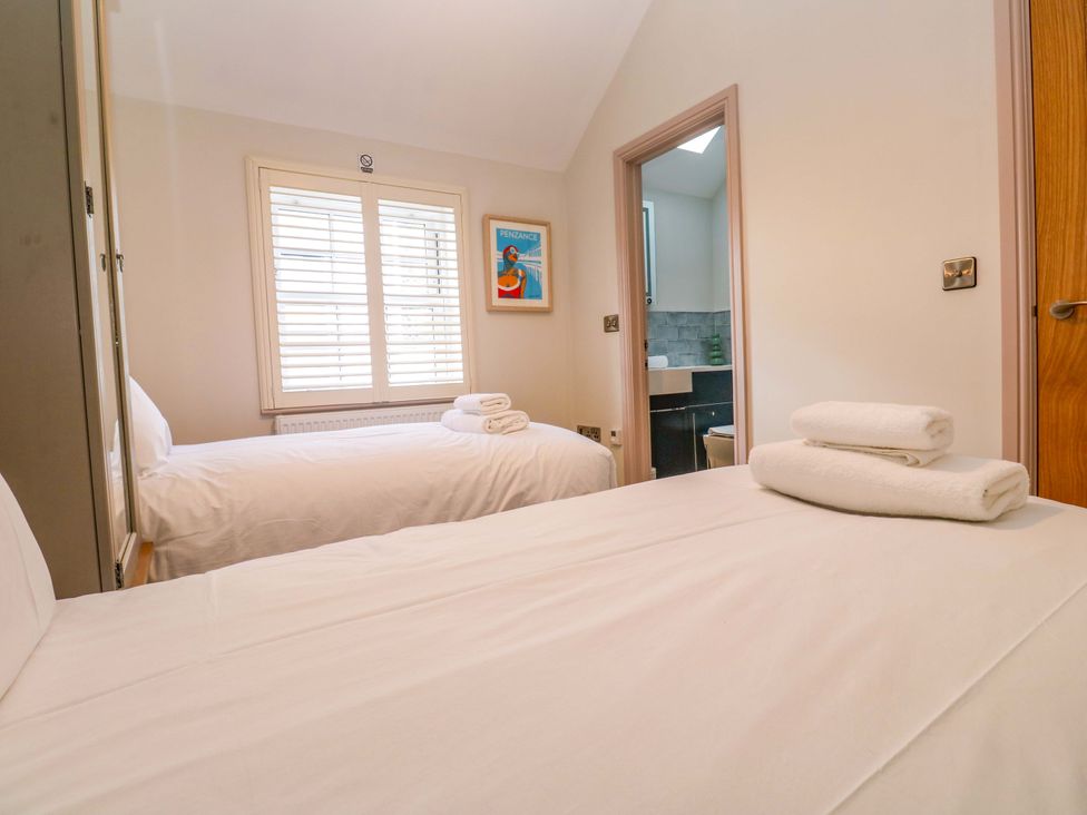 A bedroom with two beds and a bathroom visible at 21 Alverton Street Penzance