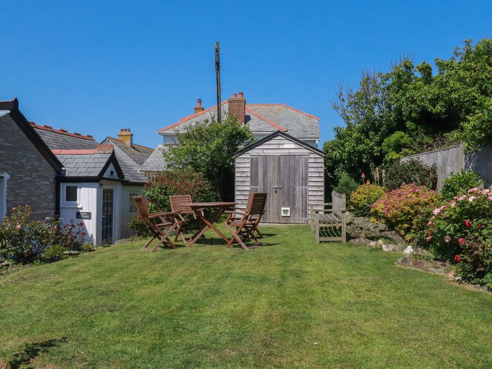 A garden with a shed and seating area at Cove Cottage in Tintagel