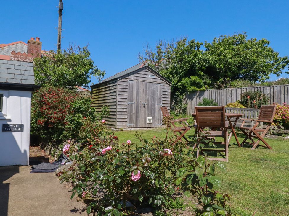 A garden with a wooden shed and outdoor furniture at Cove Cottage in Tintagel