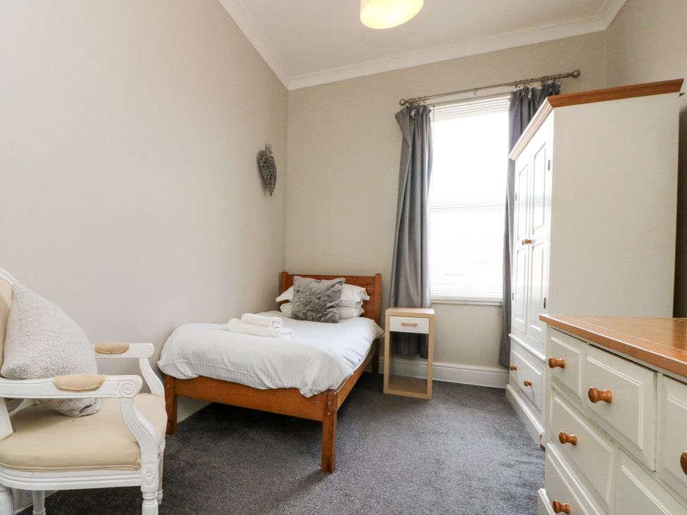 A bedroom with a bed, armchair, wardrobe, and dresser at Royal Victoria House in Scarborough