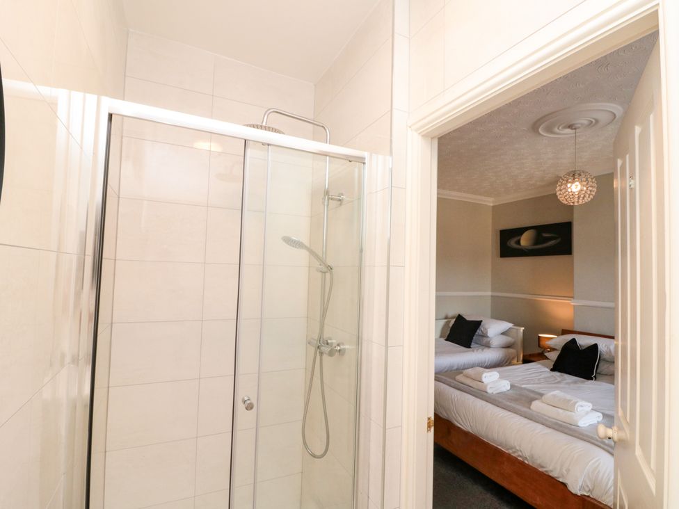 A bathroom with a shower and a view of a bedroom with two beds at Royal Victoria House in Scarborough