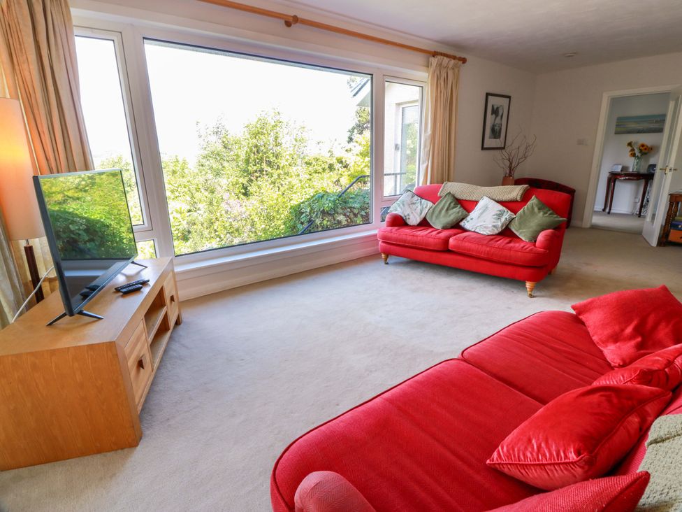 A living room with a television and red sofas at Knockendoch in New Abbey