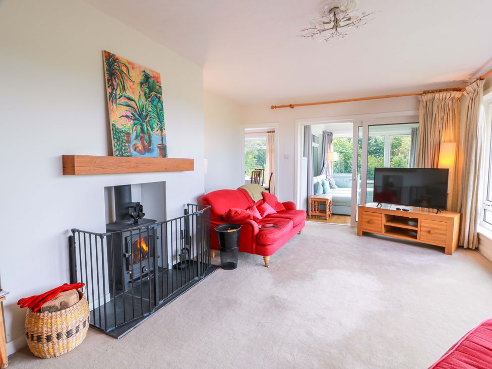 A living room with a red sofa and television at Knockendoch in New Abbey