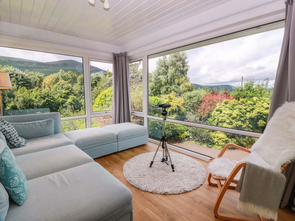 A living room with a sofa and camera tripod at Knockendoch in New Abbey
