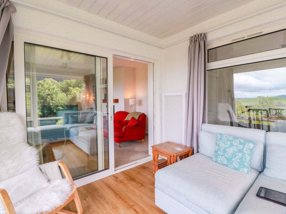 A conservatory featuring a sofa and armchair at Knockendoch in New Abbey