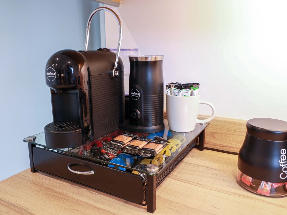 A coffee setup with a machine, frother, cup and supplies at Knockendoch New Abbey