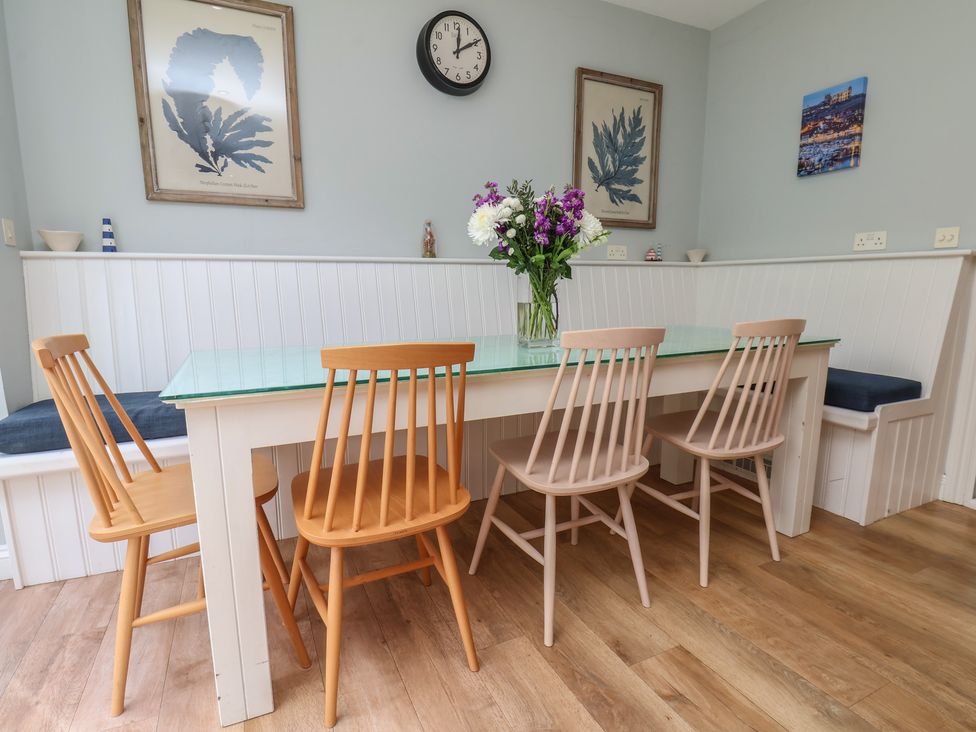 A dining room with a table, chairs, vase, and wall art at 21 Eskdaleside, Sleights
