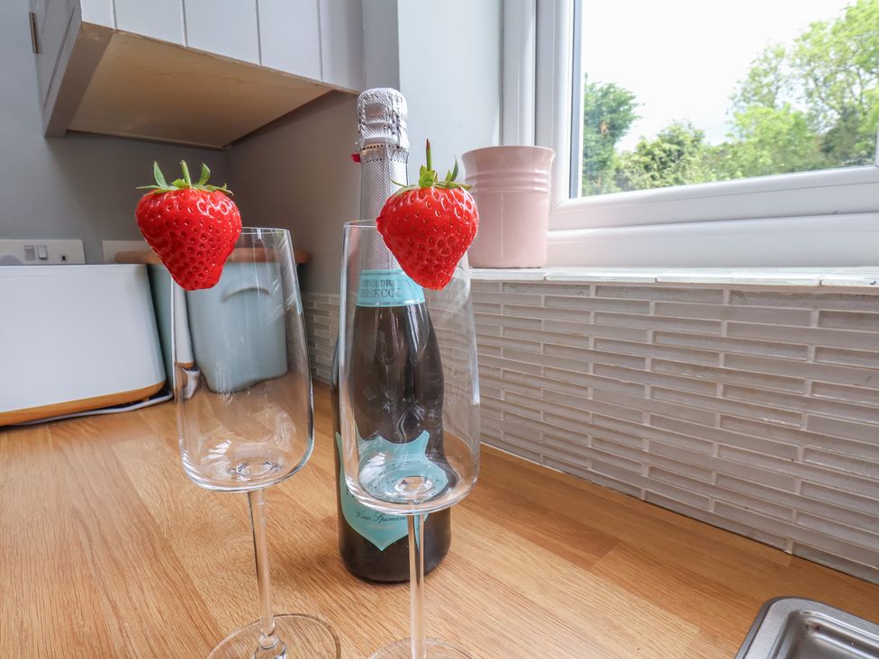 Two champagne glasses with strawberries and a champagne bottle on a countertop at 21 Eskdaleside in Sleights