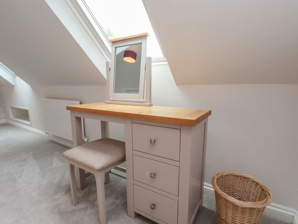 A vanity table with a mirror and chair in a bedroom at 21 Eskdaleside, Sleights