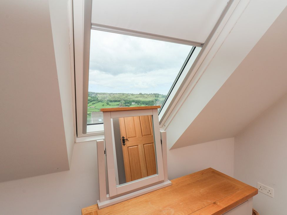 A bedroom with a mirror and a window showing a landscape at 21 Eskdaleside Sleights