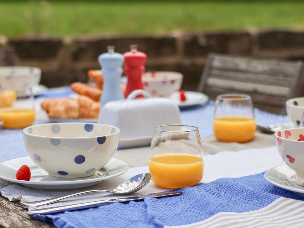 An outdoor dining table set with bowls, glasses, and croissants at 21 Eskdaleside Sleights