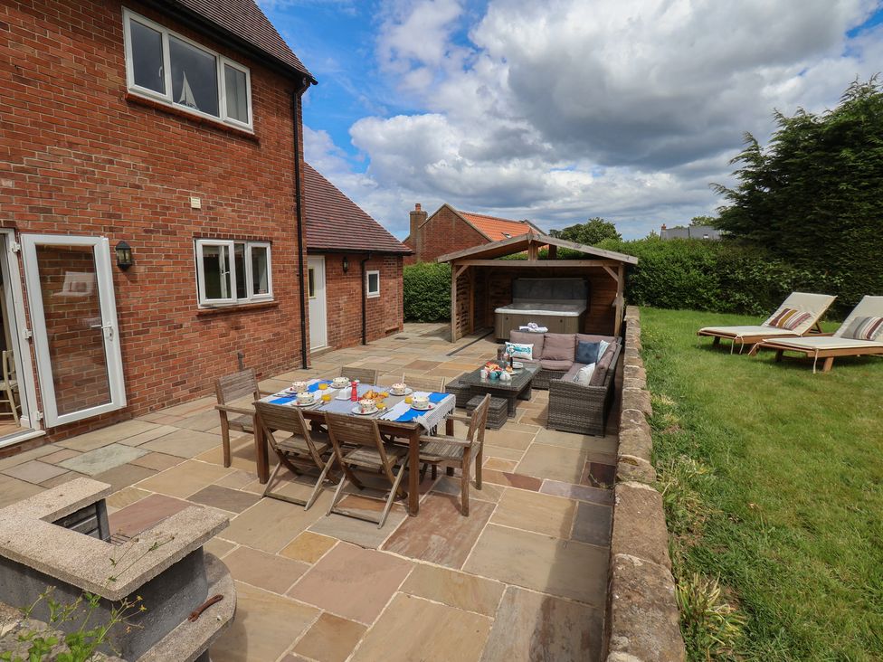 An outdoor patio with furniture and a hot tub at 21 Eskdaleside Sleights