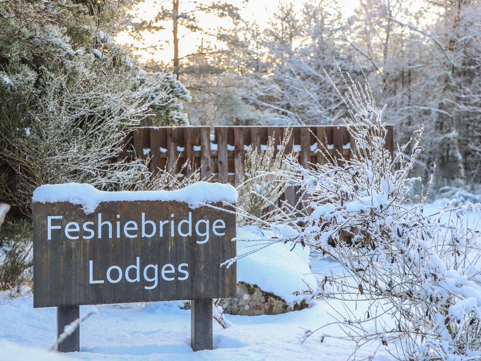 A sign for Feshiebridge Lodges surrounded by snow at Wildcat Lodge Feshiebridge near Aviemore