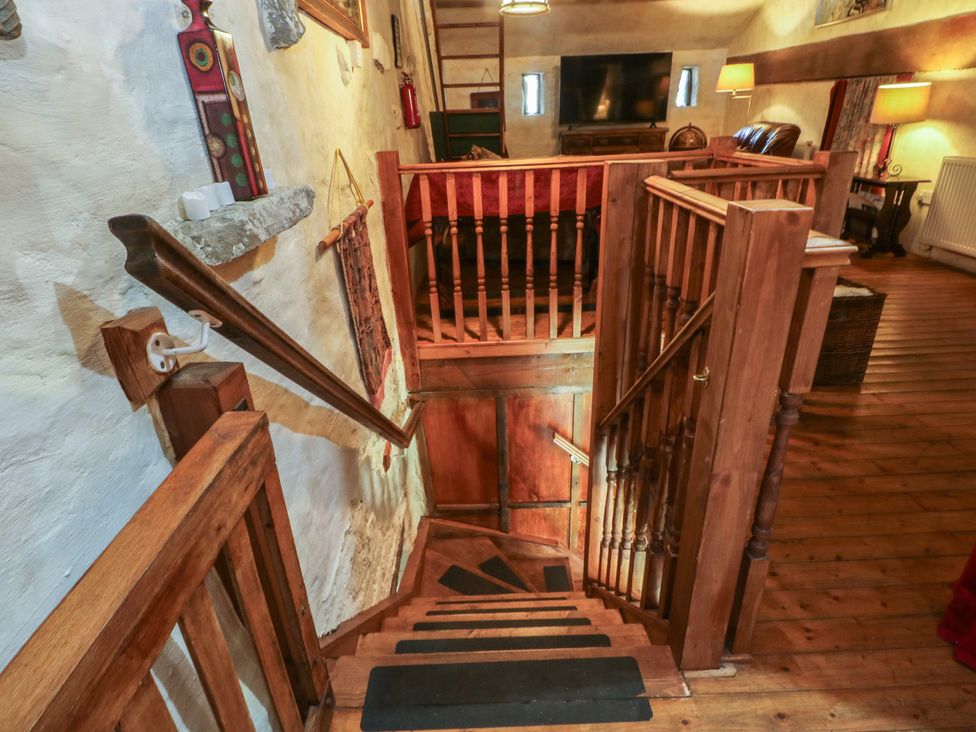 A staircase with wooden railings and a view of a living area at Moldy Warp Barn in Haworth